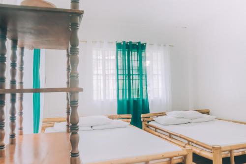 a room with two beds and green curtains at Hera Maria Hotspring Resort in Calamba