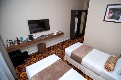 a hotel room with two beds and a flat screen tv at Garden Hotel in Bishkek