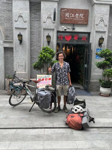 a man standing in front of a building with a bike at Riverside International Youth Hostel阅江老院青年旅舍 in Chongqing