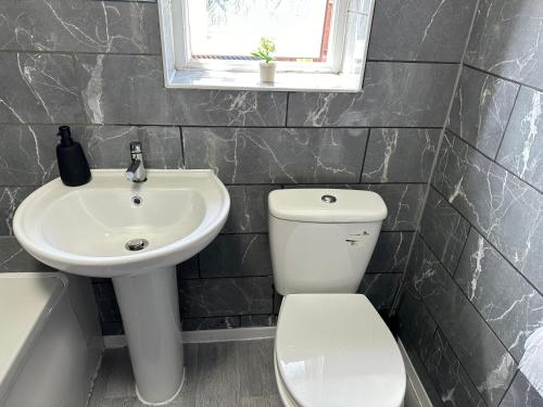 a bathroom with a white toilet and a sink at Affluent Living Property perfect for contractors and individuals in Wigan