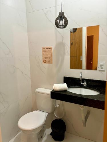 a bathroom with a toilet and a sink and a mirror at Pousada Escotilha in Arraial do Cabo