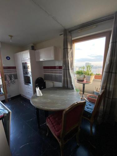 une cuisine avec une table et des chaises ainsi qu'une fenêtre dans l'établissement Chez Mado JOP2024, à Montreuil