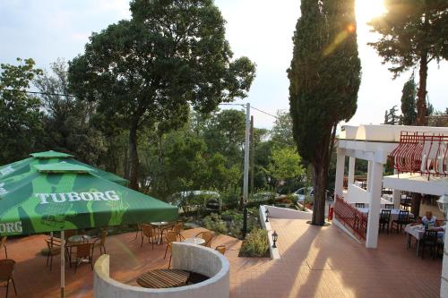 a patio with a green umbrella and tables and chairs at Pansion Ruža in Novi Vinodolski
