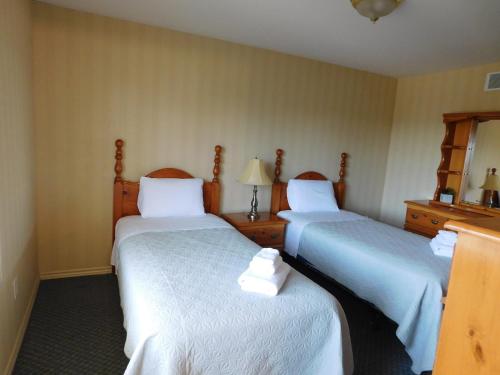 a hotel room with two beds with white sheets at Rainbow Bed & Breakfast in Niagara Falls