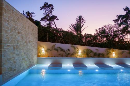a swimming pool in a house with a wall and lights at Phos Hotel Adults Only in Plataniás