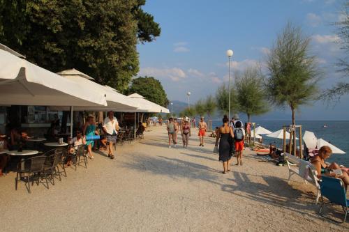 a group of people walking on a beach near the water at Pansion Ruža in Novi Vinodolski