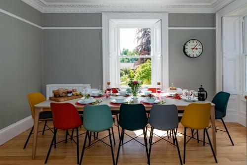 a dining room table with chairs and a clock on the wall at Rosebank House - 12 Guests, 6 Ensuite Bedrooms, EV point, Games Rooms, Wood Burner, Pet Friendly! in Blairgowrie