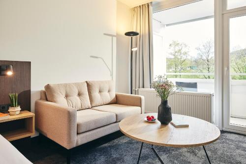 a living room with a couch and a table at Sauerland Stern Hotel in Willingen