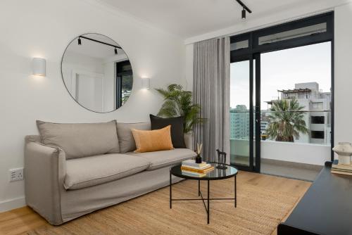 a living room with a couch and a mirror at The Sage Luxury Apartment Hotel in Cape Town