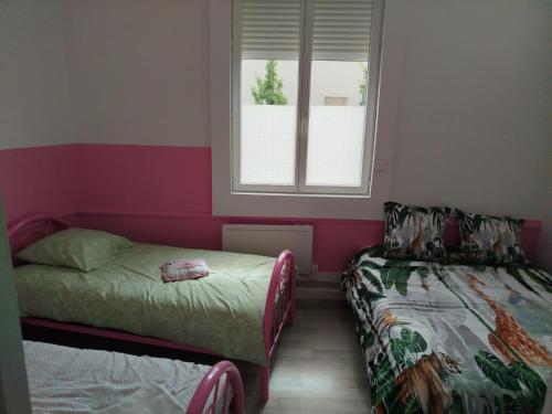 a small room with two beds and a window at maison pink flamingo aeroport tillé 2 a 4 personnes in Tillé