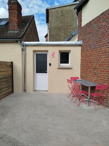 a patio with red chairs and a table in front of a garage at maison pink flamingo aeroport tillé 2 a 4 personnes in Tillé