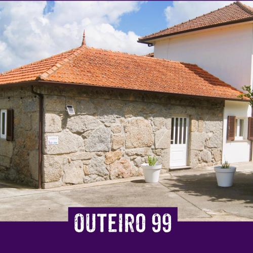 a stone building with an orange roof and a white door at Casa Outeiro 99 in Paredes de Coura