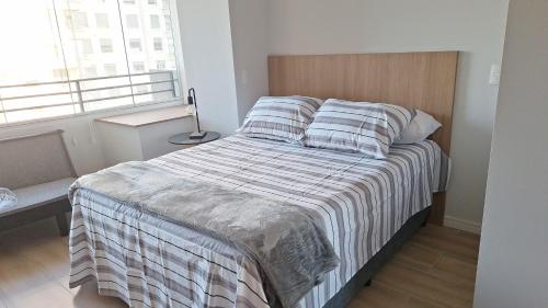 a bedroom with a large bed with a wooden headboard at Studio Butantã Novíssimo in São Paulo