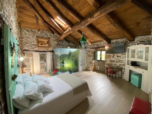 a bedroom with a large bed and a stone wall at O Forno de Catuxa Cottage & Roman Wall in Lugo
