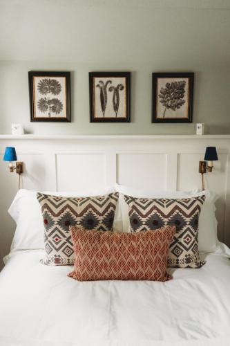 a bedroom with a white bed with four pictures on the wall at Cotswolds Manor Gatehouse with Log Burner in Bredon