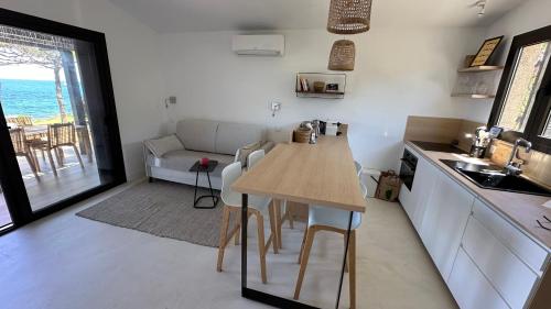 une cuisine et un salon avec une table et un canapé dans l'établissement Maison bord de mer Marine de San't Ambroggio, à Lumio