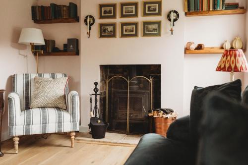 ein Wohnzimmer mit einem Kamin und 2 Stühlen in der Unterkunft Luxury Cottage with Garden in Bredon