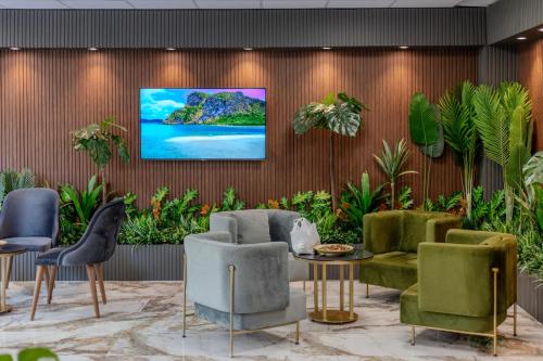 a lobby with chairs and a tv on a wall at The Business Class Hotel in Istanbul