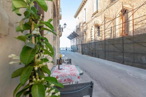an empty alley with a table with a bottle of wine at Casa Ariadne by Ortigia Apartments in Syracuse