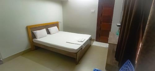 a small bed with white sheets and pillows in a room at SAN BEACH RESIDENCY in kāraikāl