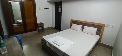 a bedroom with a bed with white sheets and a mirror at SAN BEACH RESIDENCY in kāraikāl