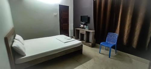 a small room with a bed and a blue chair at SAN BEACH RESIDENCY in kāraikāl