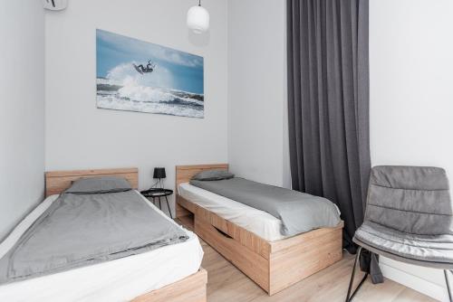 a bedroom with two beds and a chair at J7 Beržas 7A-1 in Palanga