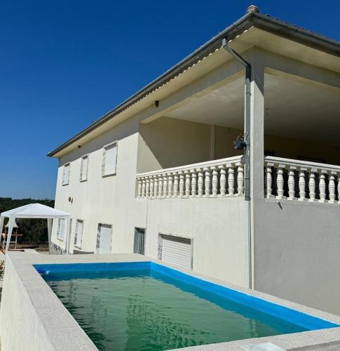 a house with a swimming pool in front of it at Villa Mendes Oliva in Almeida