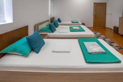a row of four beds in a room with blue pillows at Mrzenci Apartments in Gevgelija