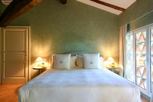 a bedroom with a large white bed with two lamps at Elizabeth Country House, a Member of Design Hotels in Minerbio