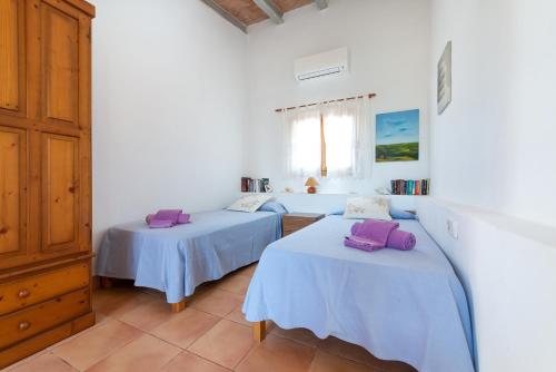 two beds in a white room with purple pillows on them at Hermosa Finca Padre in Son Servera