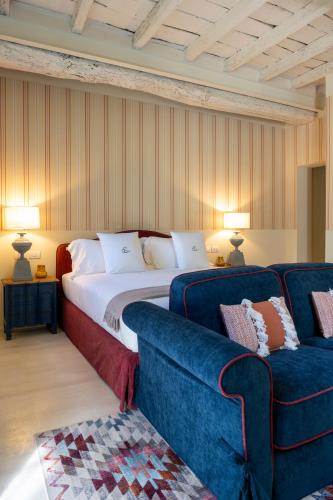a bedroom with a large bed and a blue couch at Elizabeth Country House, a Member of Design Hotels in Minerbio