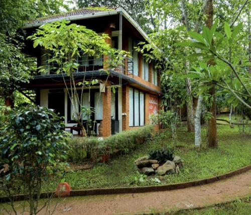 a house with a garden in front of it at Wayanad Kuruva Isles Jungle Resort in Chekadi