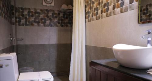 a bathroom with a sink and a toilet and a shower at Wayanad Kuruva Isles Jungle Resort in Chekadi