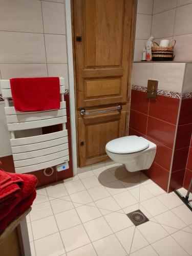 La salle de bains est pourvue de toilettes et d'une serviette rouge. dans l'établissement L'Aventure, à Châteauneuf-sur-Loire