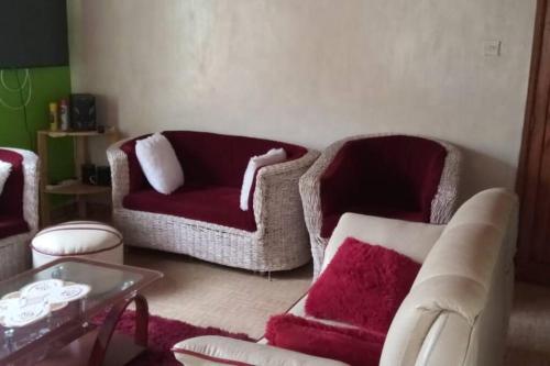 a living room with two chairs and a red couch at Full Home Busia at Nambale Gated Wifi and Electricity in Nambale