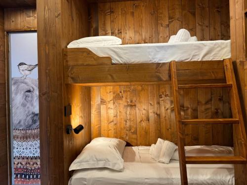 2 letti a castello in una camera in legno con scala. di Hostdomus- Bear Suite a Sestriere