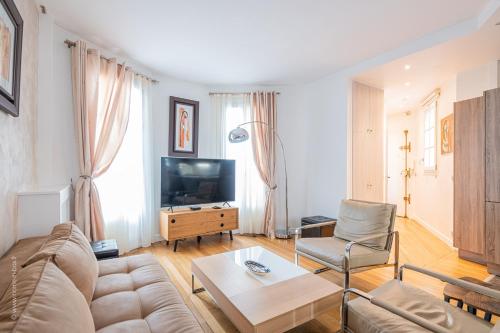 un salon avec un canapé et une télévision dans l'établissement Le Parisien ~ Champs Elysées ~ Métro, à Neuilly-sur-Seine