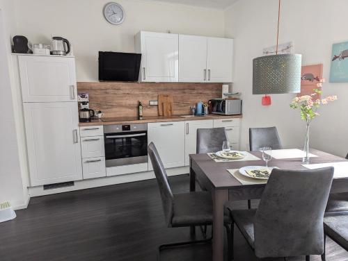 a kitchen with white cabinets and a table and chairs at Charmantes kleines Gästehaus PIA, zentral in Bedburg in Bedburg