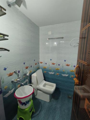 a bathroom with a toilet and a fish mural on the wall at SMS HOME STAy in Kushālnagar