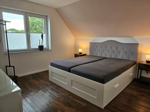 a bedroom with a large bed and two windows at Strandhaus am See in Kalkar