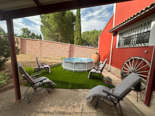 a patio with chairs and a table and a waterwheel at Casas Rurales La Picotilla y la Guija in Martiherrero