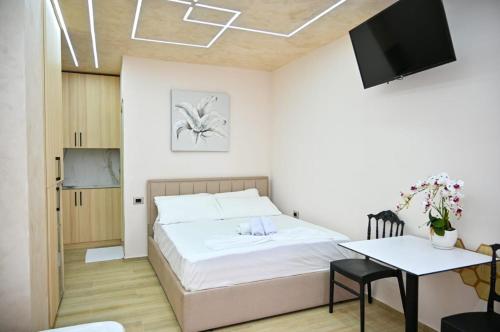 a bedroom with a bed and a table and a television at Andi Apartments in Durrës
