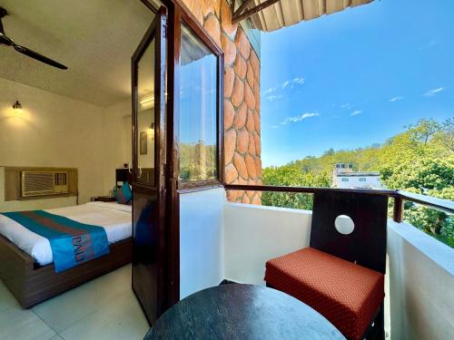 una camera da letto con un letto e un balcone con vista di Shelton Blu Resort Jim Corbett a Ramnagar
