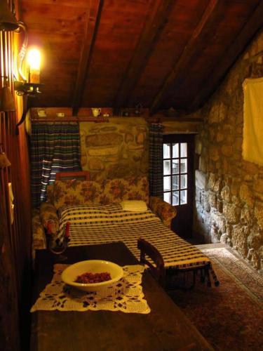 a room with a couch and a table in a stone room at Casa Campo Das Bizarras in Castro Daire