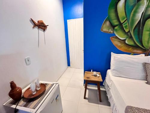 a room with a bed and a table with a clock on the wall at Pousada Nascente do Sol in Ilha de Boipeba