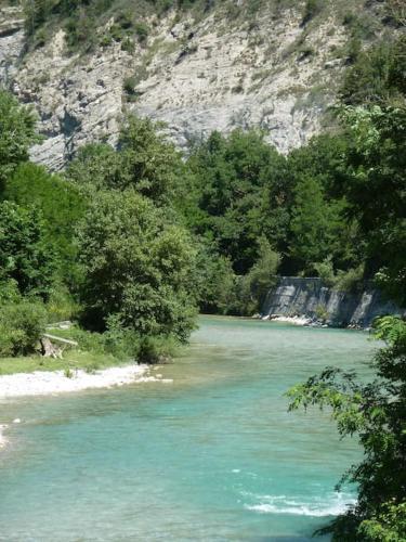a river with blue water and trees in front of a mountain at Maison en éco construction in Piégros-la-Clastre