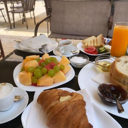 a table topped with plates of food with bread and fruit at Hotel Noel in Vlorë