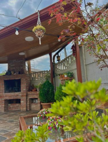 a patio with a fireplace and a table with flowers at Gold Guest House in Kutaisi