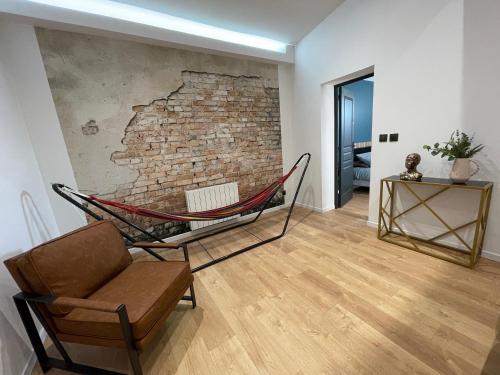 - un salon avec deux chaises et un mur en briques dans l'établissement Les 3 Suites - 6 personnes - 3 chambres avec SDB privatives, à Lens